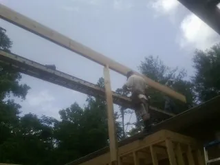 Carpenter setting a ridge beam over a new addition frame — Ice Dam Removal by Roofing Brothers in Prosperity
