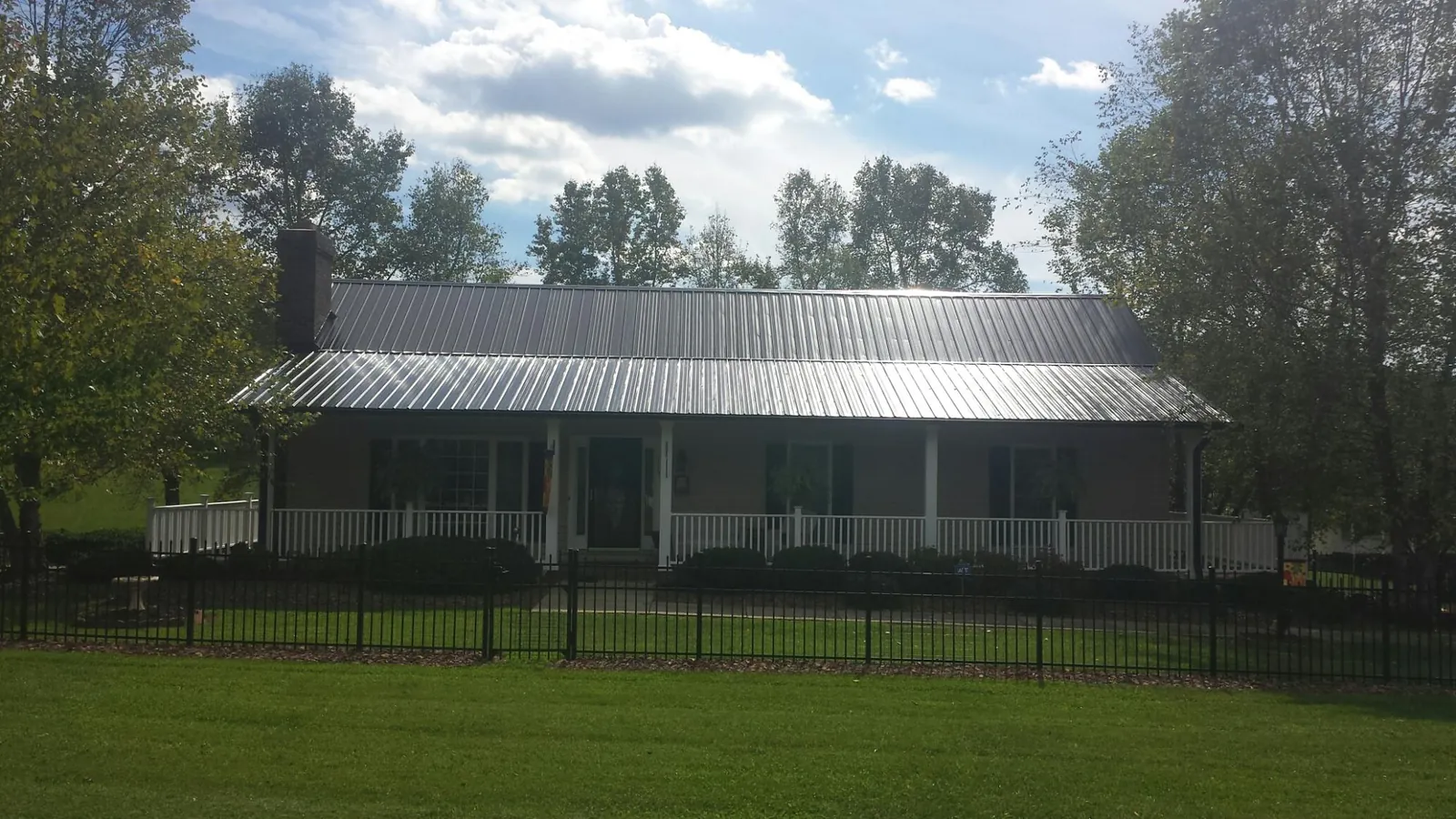 Gray metal roof on a brick ranch with a full width front porch — Gutter Guard Installation work by our crew in Prosperity