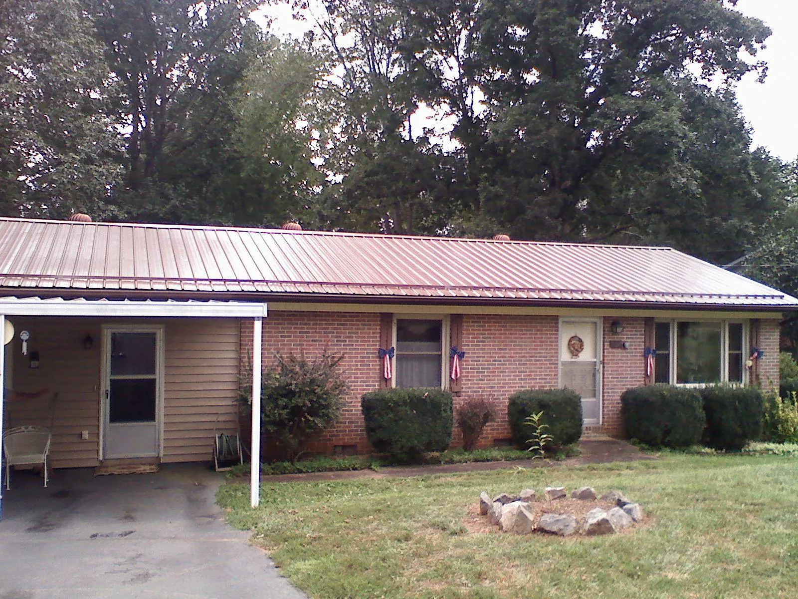 Bronze metal roof and carport on a brick ranch home — Roof Repair work by our crew in Prosperity