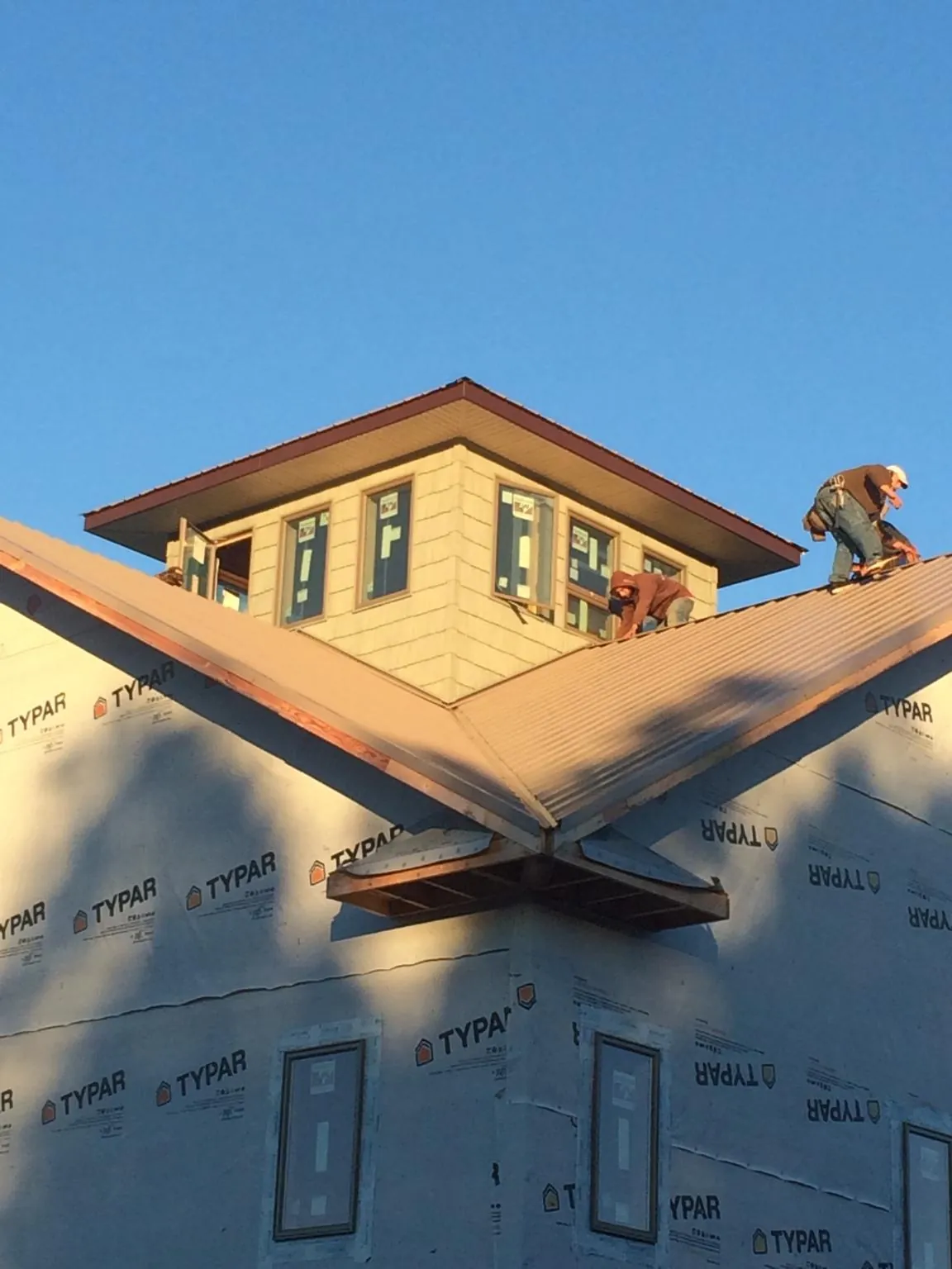 Roofers working around a rooftop cupola on a new metal roof at sunset — Roof Waterproofing in Prosperity by Roofing Brothers